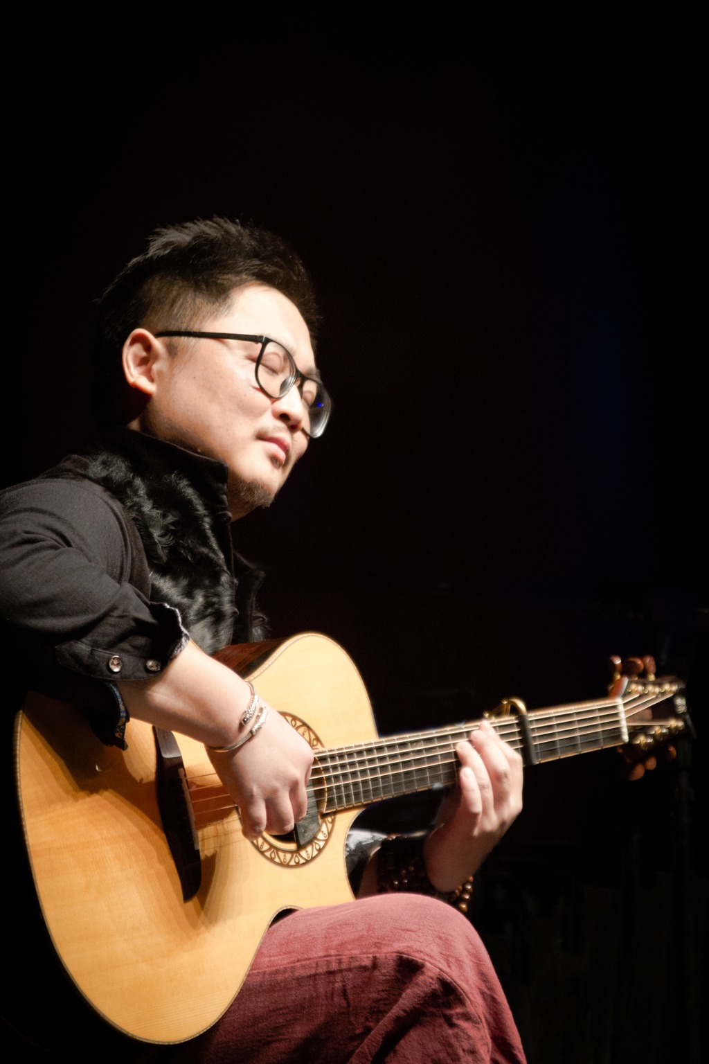 Siyi Cao playing an acoustic guitar in a close portrait